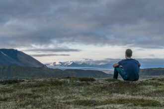 solo traveller sitting on mountain overlooking landscape and glacier view