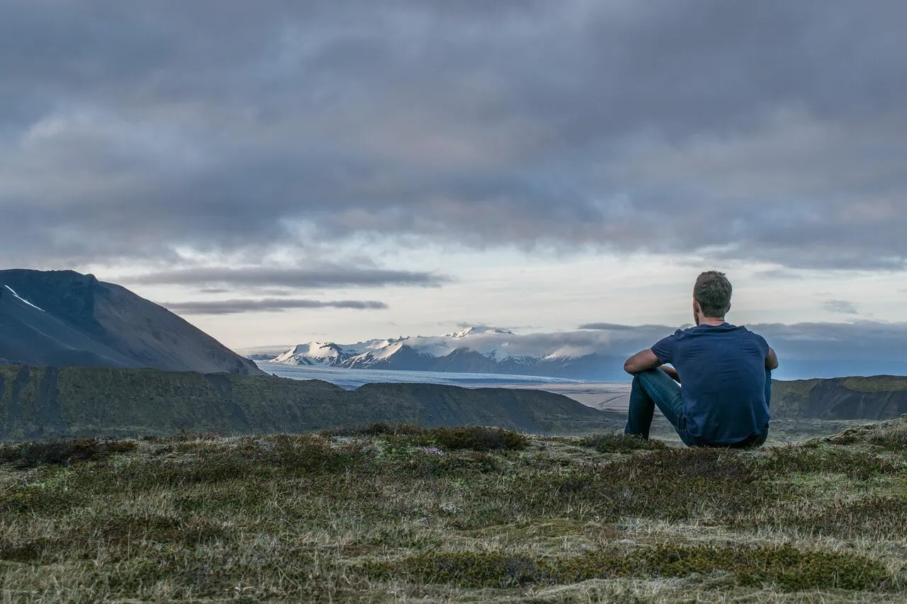 solo traveller sitting on mountain overlooking landscape and glacier view