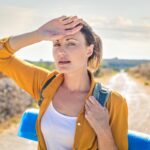 Traveller shielding herself from intense sun and heat during a hot-weather hike