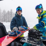 Skiers loading snowboards into a transfer vehicle