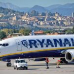 Ryanair aircraft at Milan Bergamo Airport with Bergamo's historic Città Alta and Venetian Walls visible in the background.