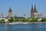 Cologne skyline viewed from the Rhine River with Cologne Cathedral and Great St. Martin Church dominating the historic cityscape.