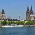 Cologne skyline viewed from the Rhine River with Cologne Cathedral and Great St. Martin Church dominating the historic cityscape.