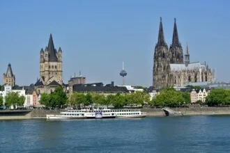 Cologne skyline viewed from the Rhine River with Cologne Cathedral and Great St. Martin Church dominating the historic cityscape.
