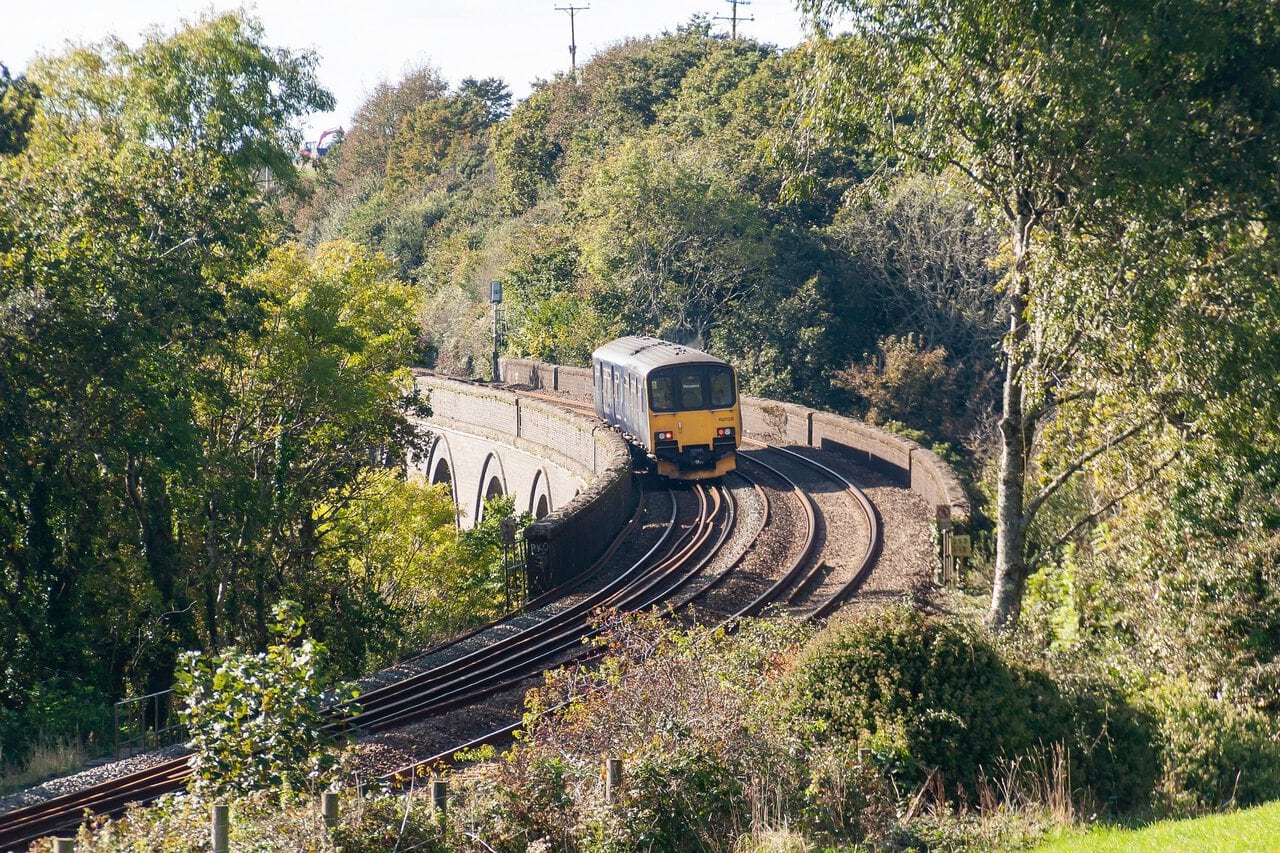 Passenger train crossing a railway viaduct in Cornwall surrounded by countryside
