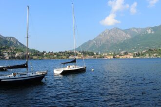 Sailing boats on Lake Lecco with the surrounding mountains, a popular day trip from Bergamo.