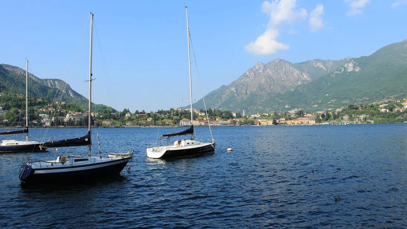 Sailing boats on Lake Lecco with the surrounding mountains, a popular day trip from Bergamo.