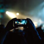 Eurovision-style concert audience recording a live performance on a smartphone.