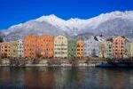 Colourful houses along the River Inn with snowy mountains behind in Innsbruck, Austria.