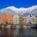 Colourful houses along the River Inn with snowy mountains behind in Innsbruck, Austria.