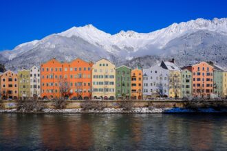 Colourful houses along the River Inn with snowy mountains behind in Innsbruck, Austria.