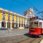 Historic Lisbon tram passing Praça do Comércio in central Lisbon, Portugal.