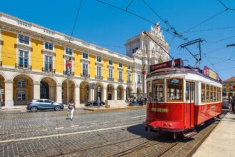 Historic Lisbon tram passing Praça do Comércio in central Lisbon, Portugal.