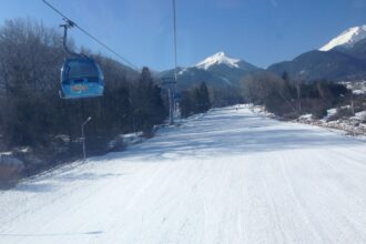 Bansko gondola lift travelling above snow-covered ski slopes in the Pirin Mountains of Bulgaria.