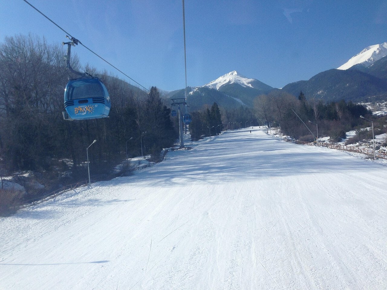 Bansko gondola lift travelling above snow-covered ski slopes in the Pirin Mountains of Bulgaria.