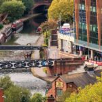 Historic Birmingham canals at Brindleyplace with narrowboats, bridges, waterside buildings and canal-side walkways.