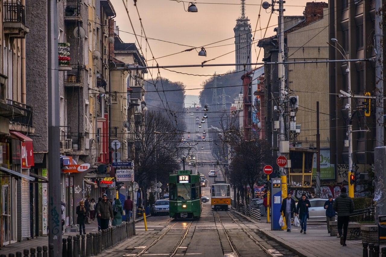 Tram travelling through central Sofia with city buildings and busy streets.