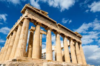 The Parthenon on the Acropolis of Athens beneath a bright blue sky.