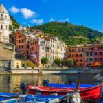 Colourful fishing boats moored in Vernazza harbour with traditional Ligurian houses behind.