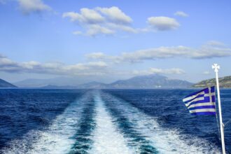 Greek flag and ferry wake on the Aegean Sea