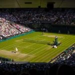 Centre Court at Wimbledon during a tennis match in front of a full crowd.