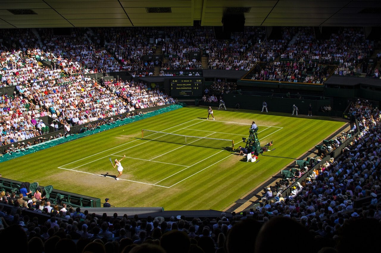 Centre Court at Wimbledon during a tennis match in front of a full crowd.