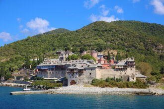 Mount Athos monastery viewed from a sightseeing cruise sailing along the Holy Mountain coastline.