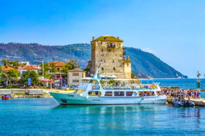 Ouranoupoli harbour with the Tower of Prosphorion and sightseeing boat in Halkidiki, Greece.