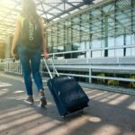 Traveller pulling a suitcase outside an airport terminal before using Stasher luggage storage.