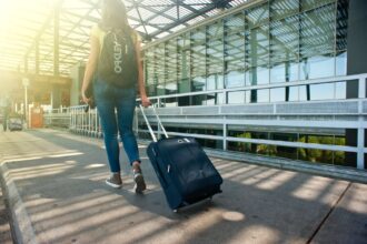 Traveller pulling a suitcase outside an airport terminal before using Stasher luggage storage.