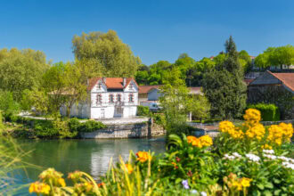 Colourful flowers overlooking the River Charente with traditional houses and riverside scenery in Cognac, France.