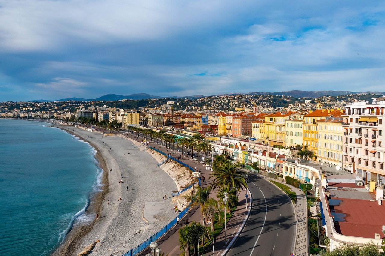 View across the Promenade des Anglais, pebble beach and colourful waterfront buildings in Nice