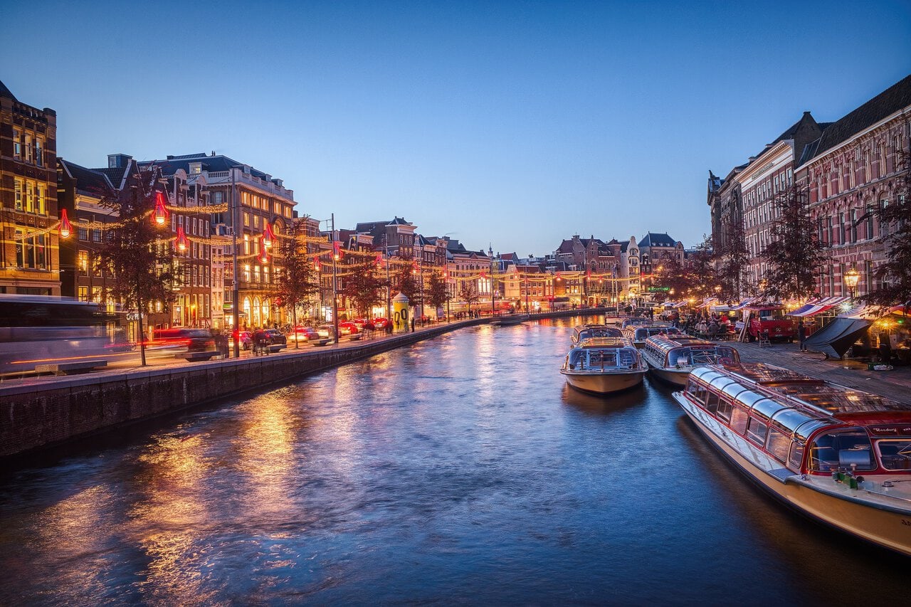 Canal cruise boats on an Amsterdam canal at dusk