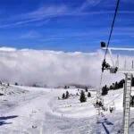 Chairlift carrying skiers above the snow-covered slopes of Kalavryta Ski Centre in Greece.