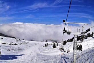 Chairlift carrying skiers above the snow-covered slopes of Kalavryta Ski Centre in Greece.