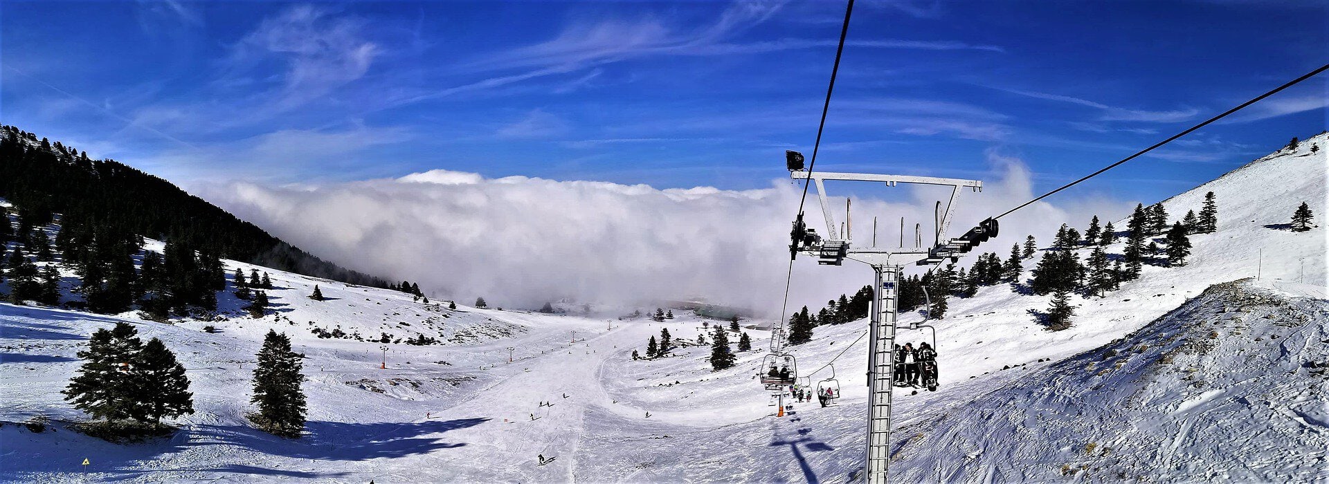Chairlift carrying skiers above the snow-covered slopes of Kalavryta Ski Centre in Greece.