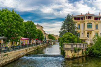 Colourful canal-side houses and antique shops reflected in the River Sorgue in L'Isle-sur-la-Sorgue, Provence