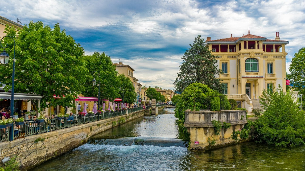 Colourful canal-side houses and antique shops reflected in the River Sorgue in L'Isle-sur-la-Sorgue, Provence
