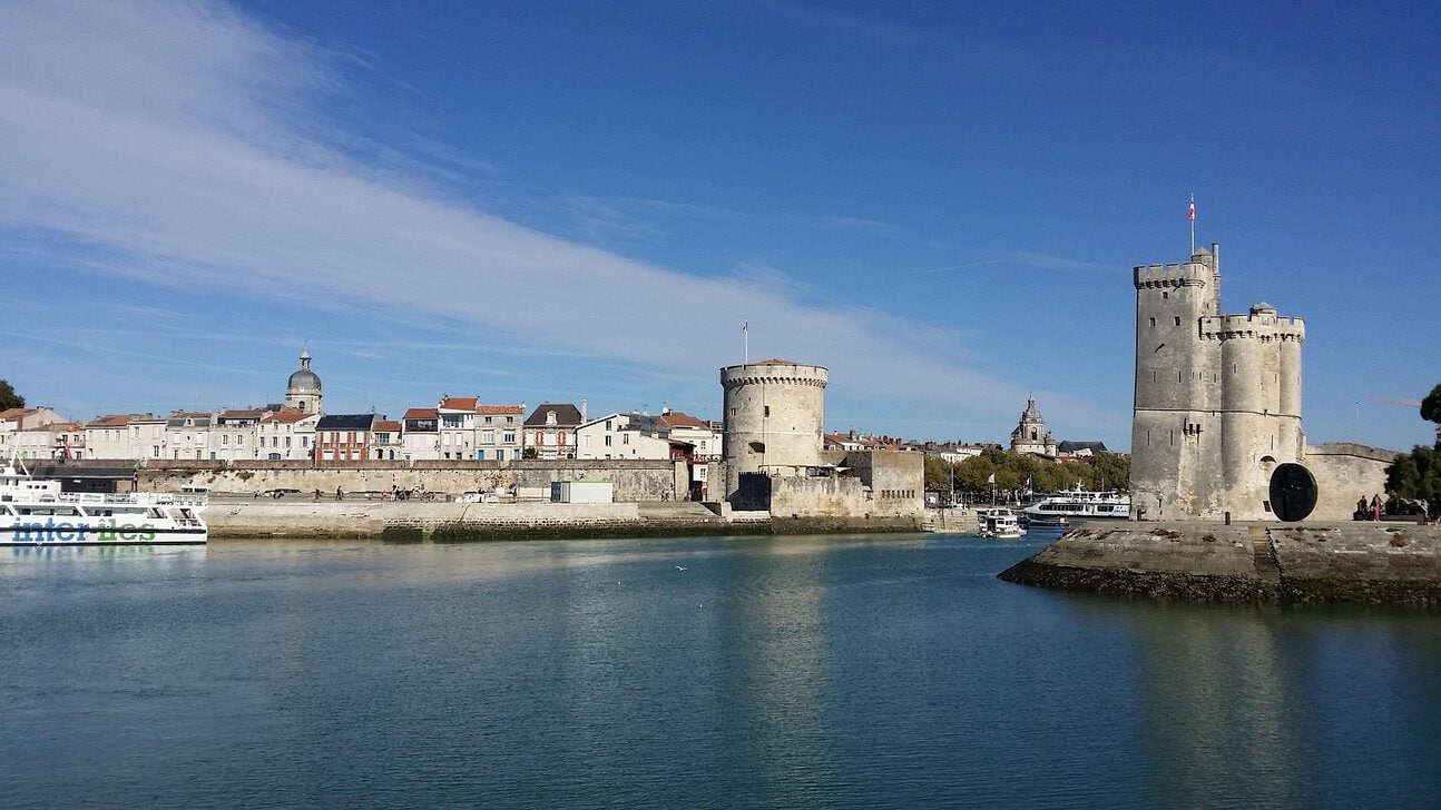 Aerial view of La Rochelle Airport terminal with the city's Old Port and Atlantic coastline in the background