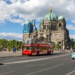 Red hop-on hop-off sightseeing bus passing Berlin Cathedral in Berlin
