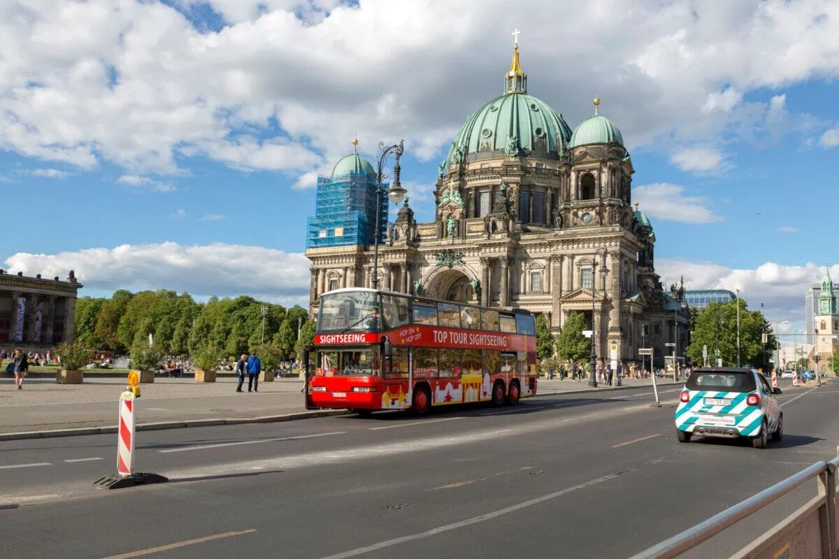 Red hop-on hop-off sightseeing bus passing Berlin Cathedral in Berlin