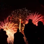 Crowds watching a red and gold Bonfire Night fireworks display in the UK