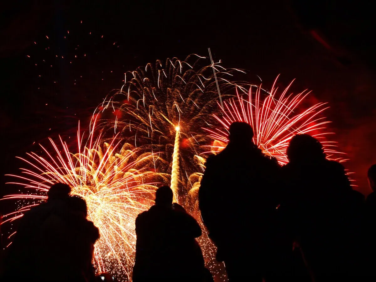 Crowds watching a red and gold Bonfire Night fireworks display in the UK
