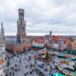 Christmas market stalls in Markt Square beneath the Belfry of Bruges, Belgium