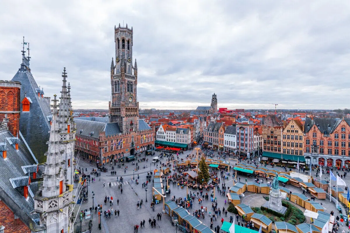 Christmas market stalls in Markt Square beneath the Belfry of Bruges, Belgium