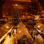 Riga Christmas market with festive stalls and a decorated Christmas tree in Dome Square at night