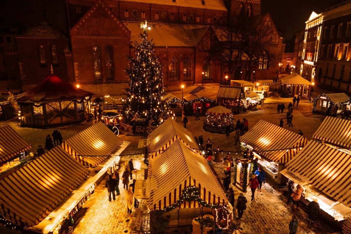 Riga Christmas market with festive stalls and a decorated Christmas tree in Dome Square at night