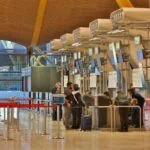 Passengers checking in at airline desks inside a European airport terminal