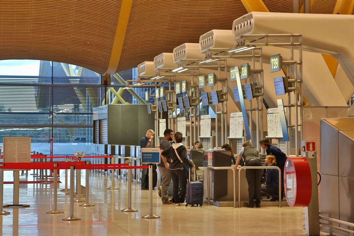 Passengers checking in at airline desks inside a European airport terminal