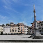 Historic square in Udine with a stone column and colourful Italian buildings